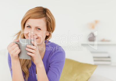 Smiling red-haired woman holding a cup of coffee