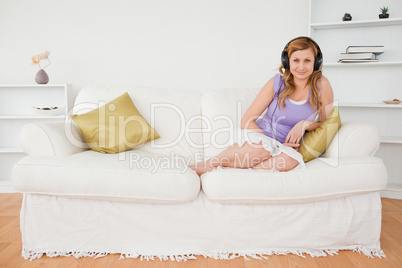 Good looking red-haired woman listening to music and posing whil