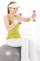 Fitness teenager woman with dumbbell sit on ball