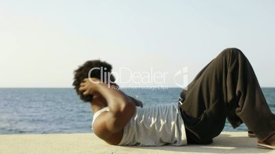 Young african american man exercising abs near the sea