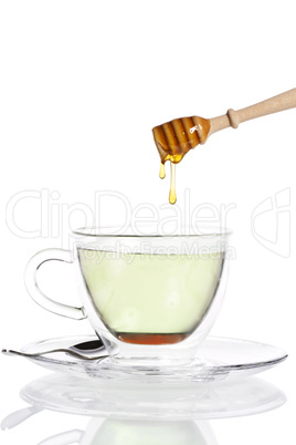 honig tropft von einem honiglöffel in grünen tee
