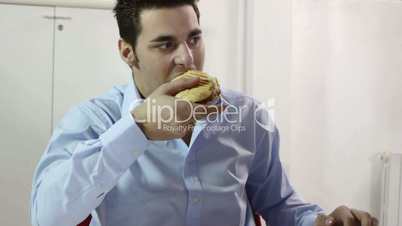 Young businessman eating junk food in office
