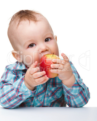 Little child is eating red apple