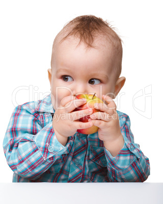 Little child is eating red apple