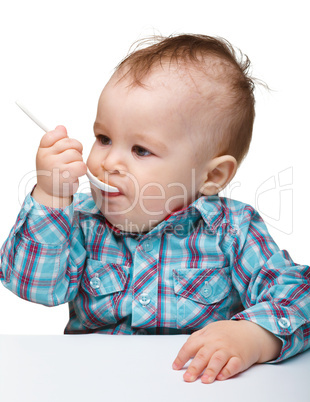 Cute little boy is biting spoon
