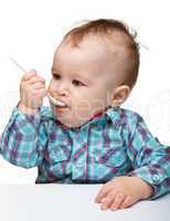 Cute little boy is biting spoon