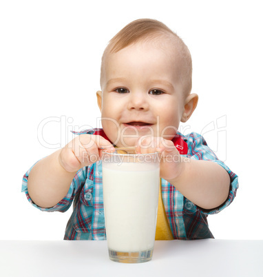 Cute little boy is holding big glass of milk