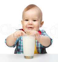 Cute little boy is holding big glass of milk
