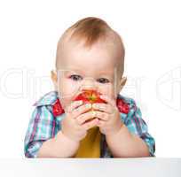 Little child is eating red apple