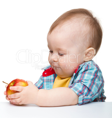 Little child is eating red apple