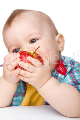 Little child is eating red apple