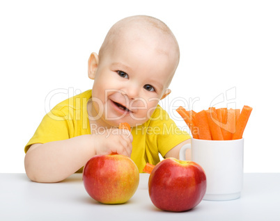 Cute little boy eats carrot and apples