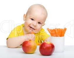 Cute little boy eats carrot and apples