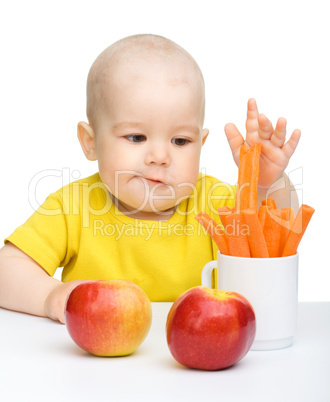 Little boy pulling up carrot from a cup