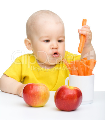 Little boy pulling up carrot from a cup