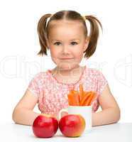 Cute little girl eats carrot and apples