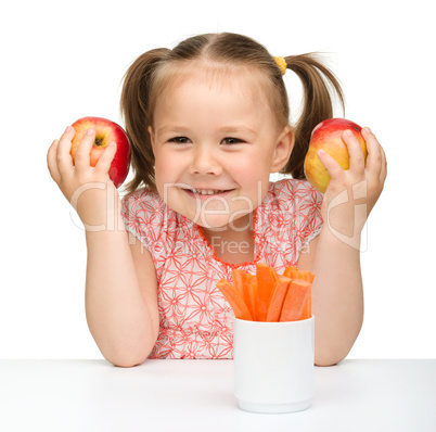 Cute little girl eats carrot and apples