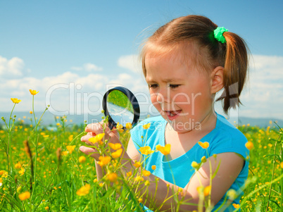 Little girl examining flowers using magnifier