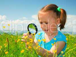 Little girl examining flowers using magnifier