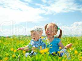 Two children are having fun on green meadow