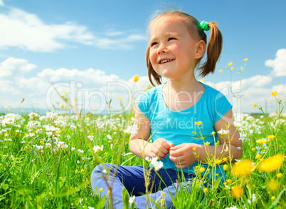 Little girl is playing on green meadow