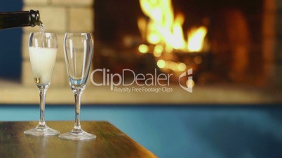 Flutes and bottle of champagne near fireplace