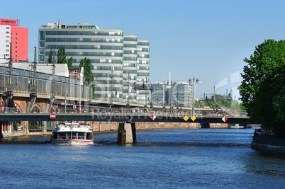 Drei Hochhäuser hintereinander an der Spree mit Brücke und Bahnstrecke