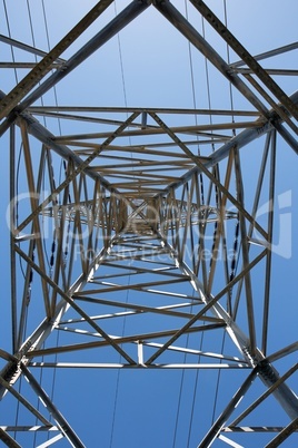 Upward view of the steel support of overhead power transmission line against blue sky