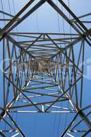 Upward view of the steel support of overhead power transmission line against blue sky