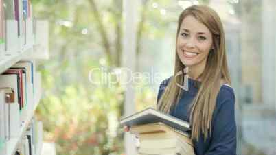 Girl choosing book in library and smiling