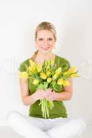 Happy woman hold bunch of tulips sitting