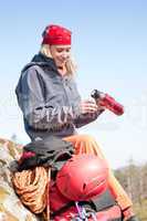 Active woman rock climbing with thermosbottle