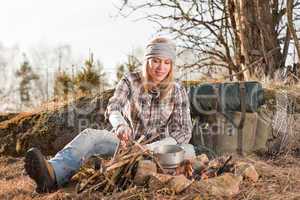 Hiking woman with backpack cook by campfire