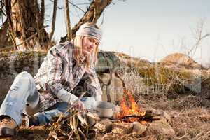 Hiking woman with backpack cook by campfire