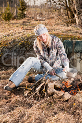 Hiking woman with backpack cook by campfire