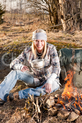 Hiking woman with backpack cook by campfire