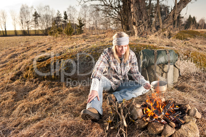 Hiking woman with backpack cook by campfire