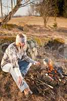 Hiking woman with backpack cook by campfire