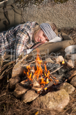 Hiking woman with backpack sleep by campfire