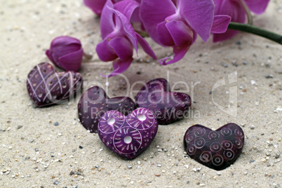 Herz und Orchideenblüte im Sand