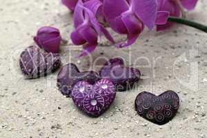 Herz und Orchideenblüte im Sand