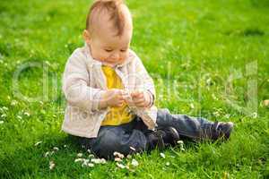 Little boy is sitting on green meadow