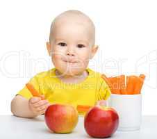 Cute little boy eats carrot and apples