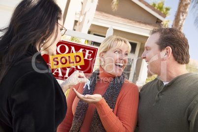 Hispanic Female Real Estate Agent Handing Keys to Excited Couple