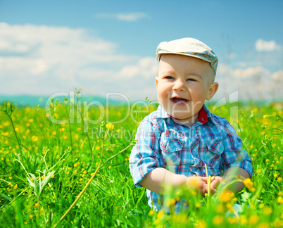 Little boy is playing on green meadow