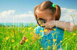 Little girl examining flowers using magnifier