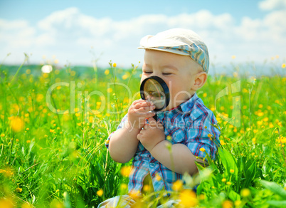 Little boy is playing with magnifier