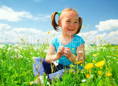 Little girl is playing on green meadow