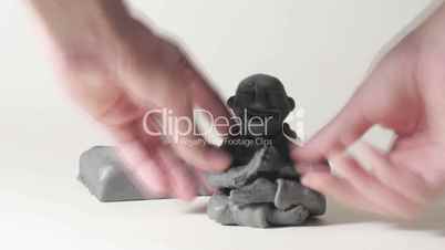 timelapse sculptor modeling plasticine cartoon figure of sitting man
