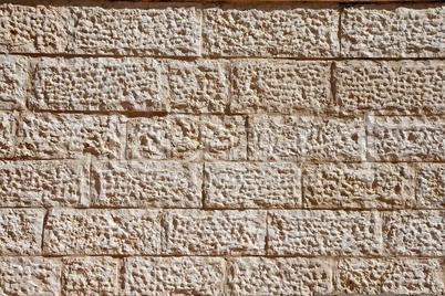 Wall built of rough beige stone blocks